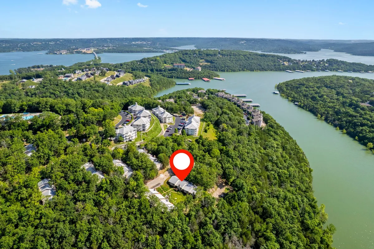 A scenic view of the lake framed by trees, with resort residential buildings visible in the distance. The landscape hints at nature trails, boating, and the tranquility of exploring the outdoors right from the property’s doorstep.