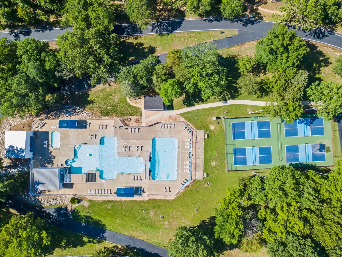 This image showcases swimming pools and tennis courts surrounded by lounge chairs and lush greenery. The area appears vibrant and active, hinting at a range of outdoor activities available for all ages.