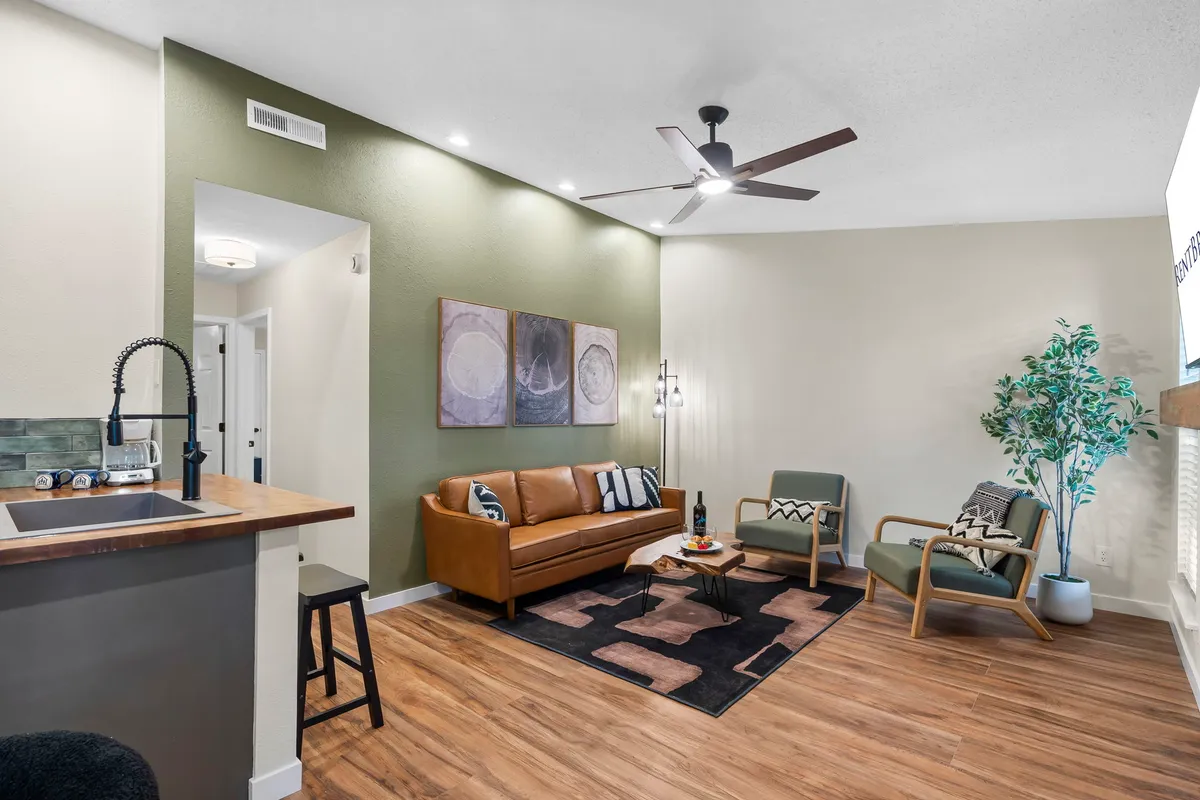 A cozy and modern living space with a leather sofa, decorative wall art, a coffee table, and a houseplant. The arrangement encourages socializing or relaxing, making it easy to supervise pets while spending time with family.